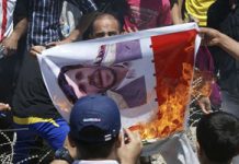 Des manifestants irakiens brûlent une affiche du président du régime iranien