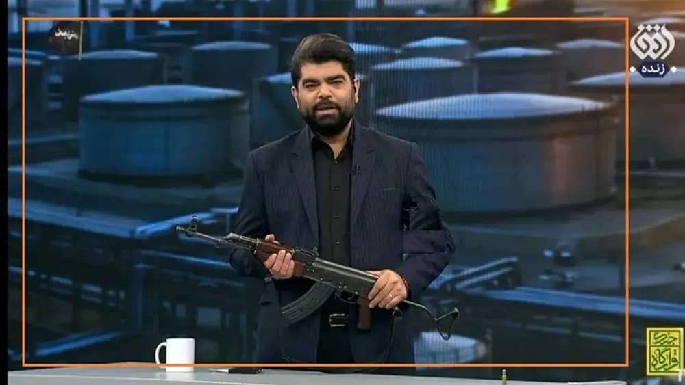 Le spectacle de la violence télévisée du régime Un présentateur de la télévision d'État iranienne pose avec un Kalachnikov en direct – mai 2026

Le 16 mai 2026, la télévision d'État iranienne a basculé dans le grand spectacle. Sur la chaîne Ofogh, le présentateur Hossein Hosseini a démonté et remonté un Kalachnikov avant de tirer à balles réelles sur un drapeau des Émirats arabes unis en studio. Le même jour, Mobina Nasiri, de la chaîne 3, a promis qu'« en cas de besoin, elle et toutes les femmes rejoindraient la guerre comme chair à canon ».

En pleine crise économique et des ressources, la chaîne IRIB 1 a présenté des exercices militaires civils dans les mosquées et sur les places publiques comme une opération de « défense publique », appelant les citoyens à économiser le carburant, l'eau et l'électricité en déclarant : « Un litre d'essence en moins, une ampoule éteinte, un seau d'eau en moins… c'est la garantie d'une défense civile réussie contre l'ennemi. »

Ces émissions n'avaient rien à voir avec l'armement du peuple iranien. Le régime sait que ce serait la chose la plus dangereuse qu'il puisse faire. En réalité, il continue d'exécuter quiconque se procure des armes de son propre chef ou envisage de les utiliser contre l'État. Ces démonstrations de force télévisées ne sont qu'une mise en scène politique, destinée uniquement à préserver la loyauté de sa base démoralisée – le seul fragment de capital social qui reste à la République islamique.

En orchestrant ces spectacles, le régime espère galvaniser ses fidèles démoralisés tout en intimidant une société agitée et épuisée par des crises incessantes – et en avertissant les ennemis étrangers que toute invasion terrestre les confronterait à un ennemi bien pire que l'Irak ou l'Afghanistan.

La propagande comme instrument de panique

Cette mise en scène militarisée coïncide avec des avertissements explicites de reprise des hostilités. Le média d’État Nowandish a rapporté le 16 mai qu’« un pays de la région » avait averti Téhéran, en privé, de la forte probabilité d’une reprise des combats suite à l’impasse diplomatique à Pékin. L’ancien commandant des Gardiens de la révolution et député Ismail Kowsari, s’exprimant sur IRIB News le 16 mai, a exigé une mobilisation générale : « Hommes et femmes… s’ils repèrent un point occupé par le régime sioniste ou américain, ils peuvent l’affronter.» Les rassemblements nocturnes sur la place des Martyrs d'Arak et ailleurs mettaient en scène des enfants en uniformes militaires – une simple mise en scène orchestrée par le régime.

Pourtant, la politique réelle du régime est à l'opposé de cet armement massif. Le chef de la police, Ahmadreza Radan, a annoncé le 17 mai que 6 500 « vendeurs de la patrie et espions » avaient été arrêtés depuis le début du conflit, dont 567 « cas particuliers » liés à des groupes d'opposition.

Derrière ces présentateurs brandissant des armes se cache une chute libre de l'économie.

La production d'essence est tombée à 105 millions de litres par jour, contre une demande de 135 millions, créant un déficit permanent de 30 millions de litres. De longues files d'attente s'étendent à travers Mashhad, Bandar Abbas et Jiroft. Des citoyens ont exprimé leur colère à la télévision d'État : « Dix litres d'essence ? 200 000 tomans ! Par Dieu ! » L'économiste du régime, Yazdizadeh, interviewé sur House of Economy le 16 mai, a qualifié la politique monétaire de « deux coups économiques » qui ont permis aux exportateurs de profiter de l'effondrement du rial.

Les pharmacies dressent un tableau encore plus sombre. Le 17 mai, le porte-parole de l'association, Hadi Ahmadi, a déclaré à l'agence Mehr que les dettes des assurances avaient quadruplé ; la Sécurité sociale doit à elle seule 15 000 milliards de tomans aux pharmacies privées. Les centres de dialyse refusent des patients. Le sérum et les antibiotiques sont rationnés. Ces humiliations quotidiennes expliquent la rhétorique belliqueuse et brutale du régime : il n'offre aucune solution, seulement des diversions.

Siège numérique et luttes intestines au sein de l’élite

La guerre de l’information est également perdue. Après quatre mois de coupure totale d’internet, les applications de remplacement du régime — Rubika et Bale — ont subi une panne nationale le 16 mai. Les cartes SIM irakiennes du marché noir ont proliféré, poussant des responsables de la sécurité comme Ghazanfari à s’inquiéter des « menaces à l’information et à la sécurité ». Un nouveau comité de « nettoyage » placé sous l’égide du vice-président Mohammad-Reza Aref est largement perçu comme le prélude à une tarification permanente à plusieurs niveaux d’« Internet Pro », qui soutirera encore plus d’argent aux citoyens les plus démunis. Même le député du régime, Pourdehghan, a reconnu que les citoyens étaient furieux face à la « discrimination… et à des noms étranges comme Internet Pro ».

La paralysie des factions aggrave la crise. Les factions extrémistes et révisionnistes s'affrontent publiquement sur la question de la négociation ou de l'escalade. Osman Salari, vice-président de la commission judiciaire du Majlis.

Le 17 mai, l'agence ISNA a tenu à rappeler que « le premier et le dernier mot en matière de guerre et de paix appartient exclusivement au Guide suprême ». Le président du Parlement, Ghalibaf, a été nommé subitement envoyé spécial en Chine, doté de pouvoirs élargis – une proposition du président iranien Massoud Pezeshkian, approuvée par Mojtaba Khamenei – tandis que le Shariatmadari de Kayhan a désigné l'Arabie saoudite, les Émirats arabes unis, le Koweït, le Qatar, la Jordanie et Bahreïn comme « cibles prioritaires de représailles ».

Isolement extérieur et dénouement

Sur le plan extérieur, l'aventurisme s'est retourné contre ses auteurs. Le 17 mai, une frappe de drone a touché le générateur périphérique de la centrale nucléaire de Barakah, aux Émirats arabes unis, déclenchant une alerte de l'AIEA et suscitant immédiatement des soupçons internationaux à l'encontre de Téhéran. Lors de la réunion des ministres des Affaires étrangères des BRICS à Delhi, les Émirats arabes unis ont accusé le régime iranien d'attaques répétées contre des infrastructures civiles depuis le 28 février ; aucun communiqué conjoint n'a été publié.

Le seul capital social qui reste au régime est sa base électorale démoralisée et en déclin : les fidèles les plus fervents qui participent encore aux rassemblements nocturnes et applaudissent les exercices télévisés au Kalachnikov. Chaque présentateur armé, chaque menace de fermeture du détroit d'Ormuz, chaque séance d'entraînement mise en scène dans une mosquée est un acte de désespoir visant à maintenir cette base mobilisée et le reste de la société trop terrifié ou épuisé pour agir.

Le parallèle avec la Libye, qui circule sur les réseaux sociaux iraniens, est révélateur. En 2011, un présentateur de la télévision d'État avait brandi une arme à feu quelques jours avant la chute de Kadhafi. Aujourd'hui, la télévision d'État iranienne fait de même, à une échelle bien plus vaste, tandis que le régime exécute discrètement quiconque prend le message au pied de la lettre. Plus le régime terroriste lutte pour survivre par le spectacle, plus il accélère la désintégration même qu'il redoute. Les caméras continuent de tourner, les files d'attente s'allongent, et le dénouement est enclenché.
