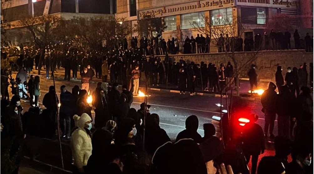 Des manifestants se rassemblent de nuit dans une rue du quartier de Jannatabad, à Téhéran, allumant de petits feux sur le trottoir — 8 janvier 2026.